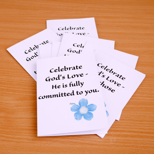Stack of greeting cards with text and a flower design on a wooden surface